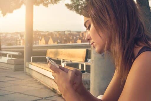 Vrouw die op haar telefoon werkt aan het verdienen van passief inkomen via internet